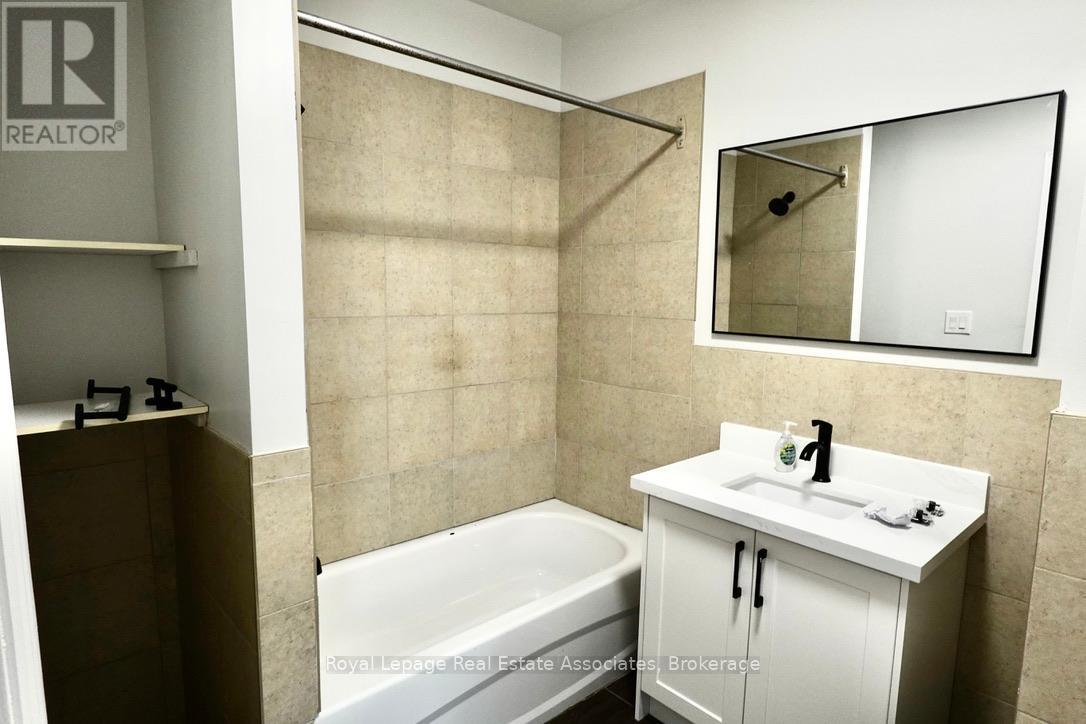 A white bathroom with a tub, sink, and mirror.