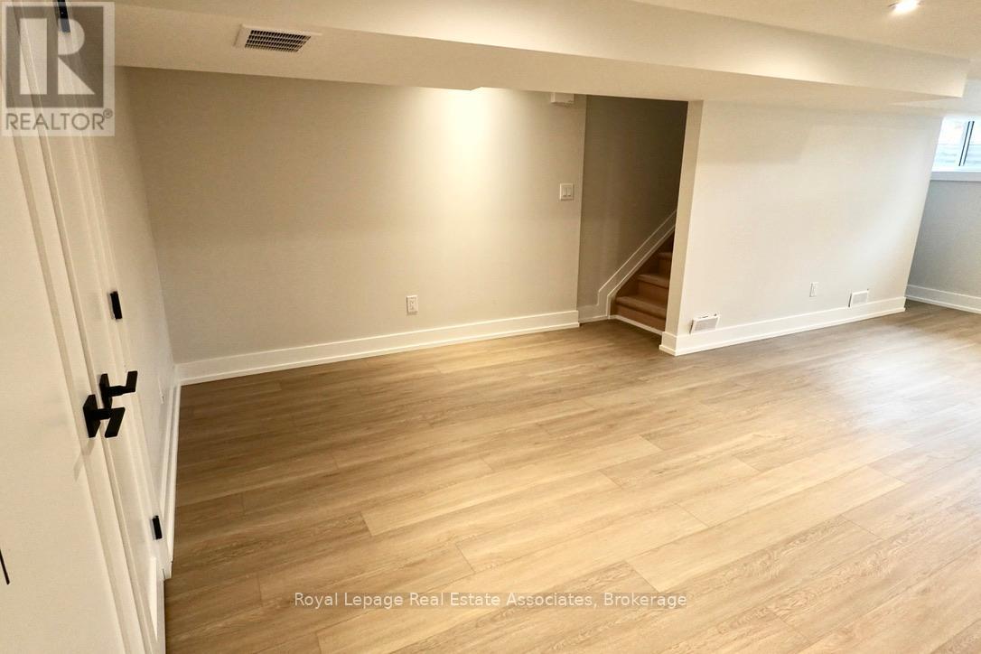A room with wooden flooring and a staircase leading to another room.