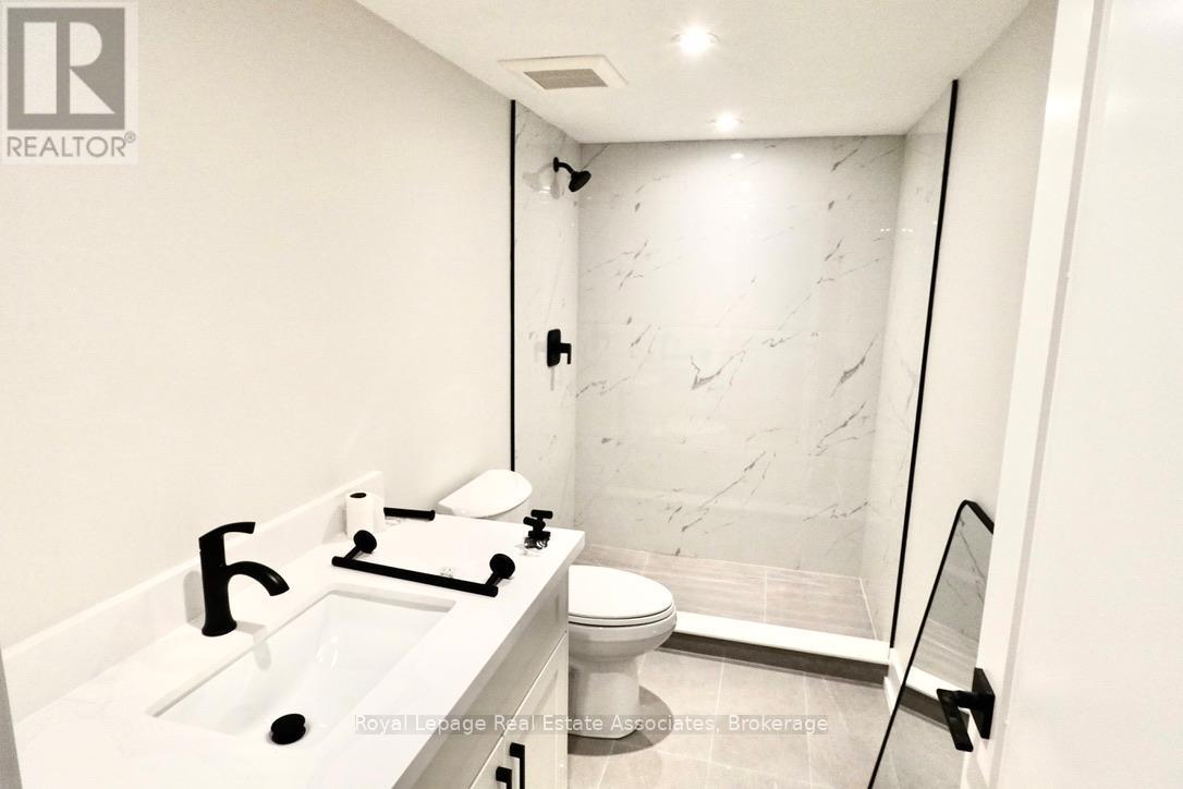 A white bathroom with a marble wall and a toilet.