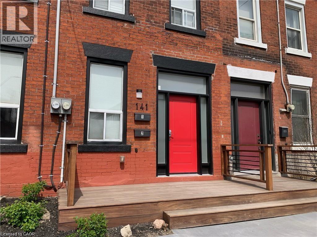 A red door is on the front of a brick building.