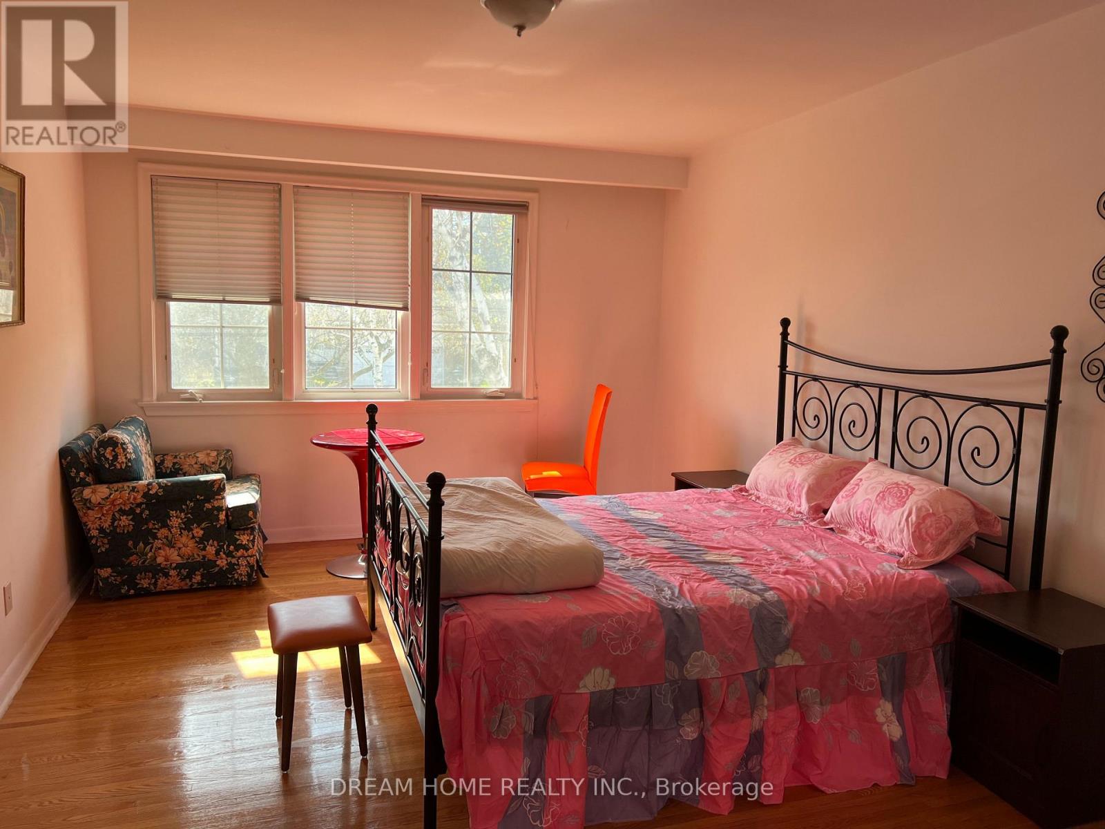 A bedroom with a bed, chair, and window.