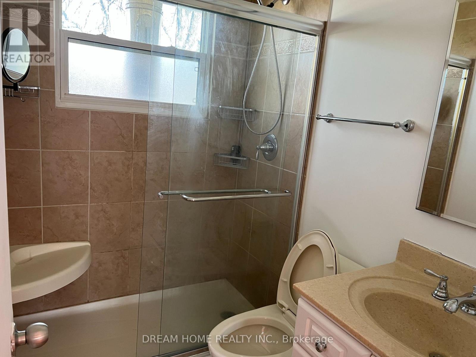A bathroom with a glass shower door and a sink.