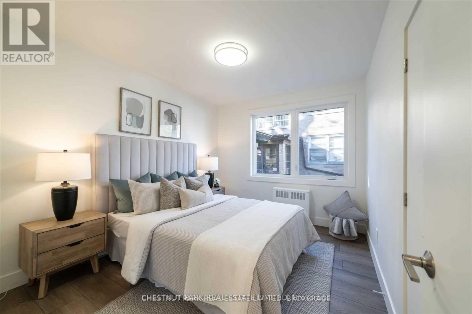 A bedroom with two beds and a nightstand with a lamp.