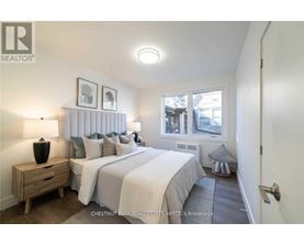 A bedroom with two beds and a nightstand with a lamp.