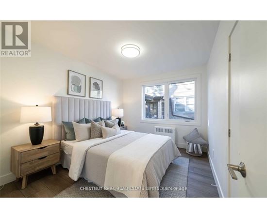 A bedroom with two beds and a nightstand with a lamp.