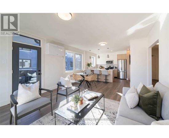 A modern living room with a grey sofa, a glass coffee table, and a dining area in the background.