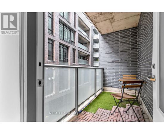 A balcony with a table and chairs overlooking a building.