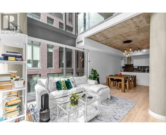 A living room with a white couch and a glass coffee table.