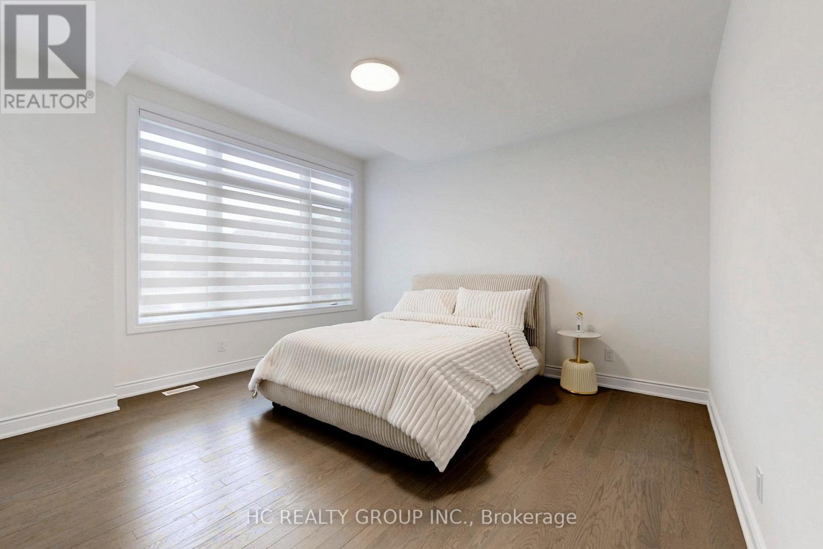 A bedroom with a bed, nightstand, and window with blinds.