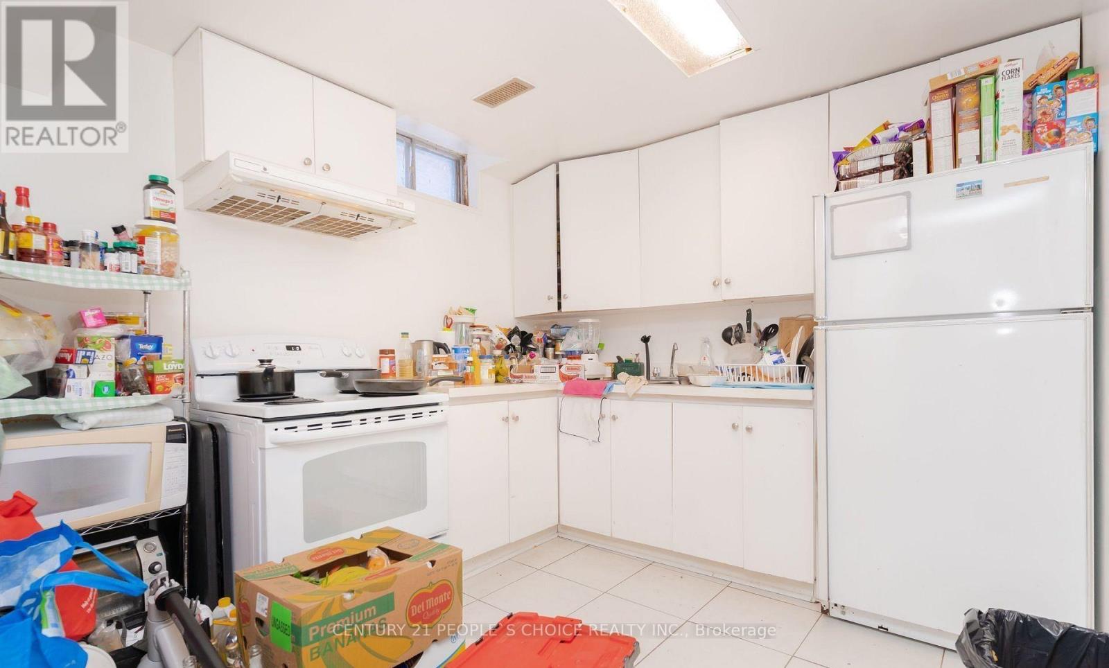 A kitchen with white appliances and cabinets is cluttered with items.