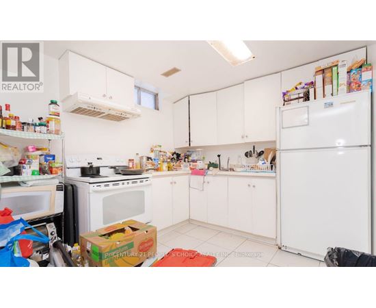 A kitchen with white appliances and cabinets is cluttered with items.
