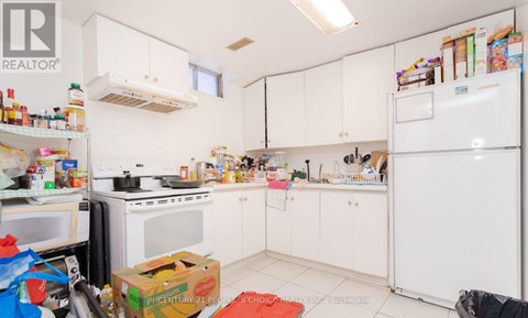 A kitchen with white appliances and cabinets is cluttered with items.