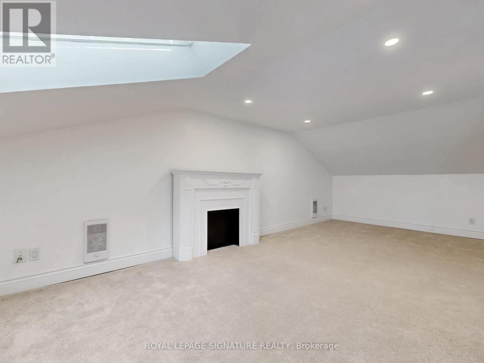 A spacious room with a fireplace and carpeted floor.
