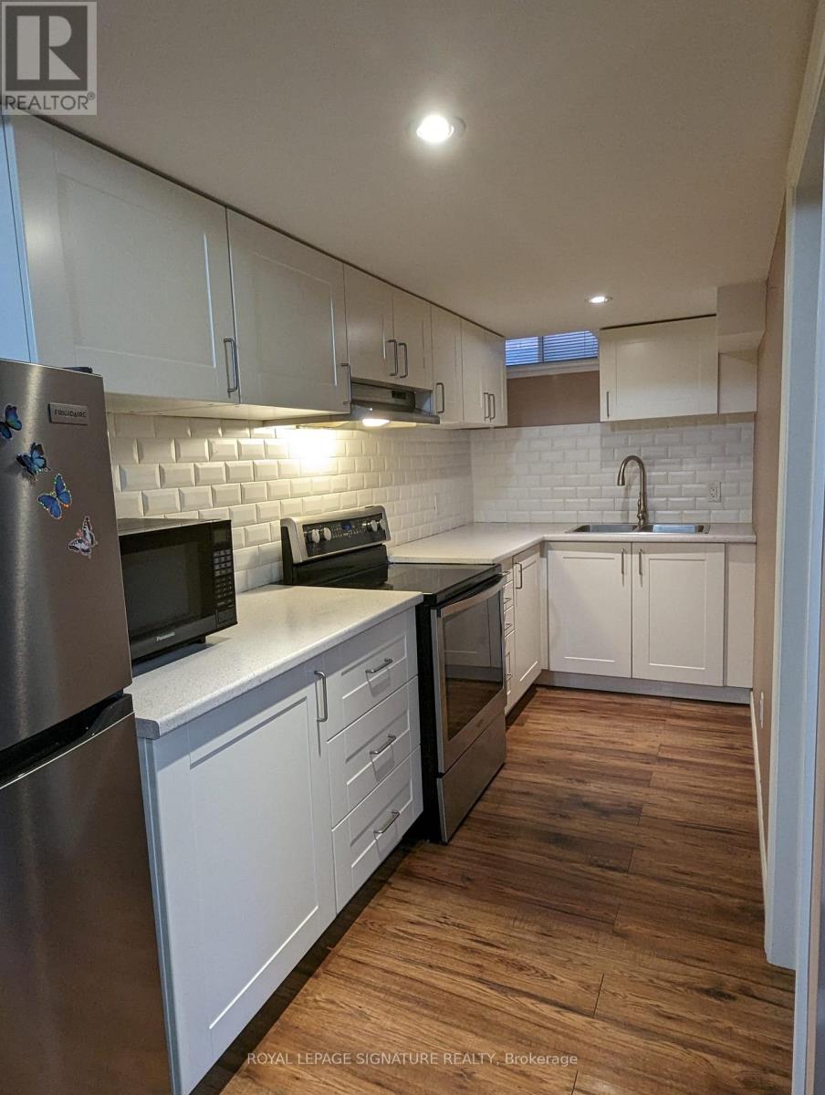 A kitchen with white cabinets and a wooden floor.