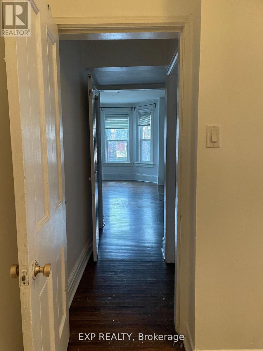 A hallway with a door on the left and a window in the distance.