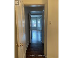 A hallway with a door on the left and a window in the distance.