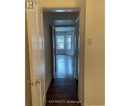 A hallway with a door on the left and a window in the distance.