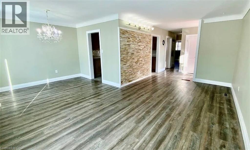 A spacious room with wooden flooring and a stone wall.