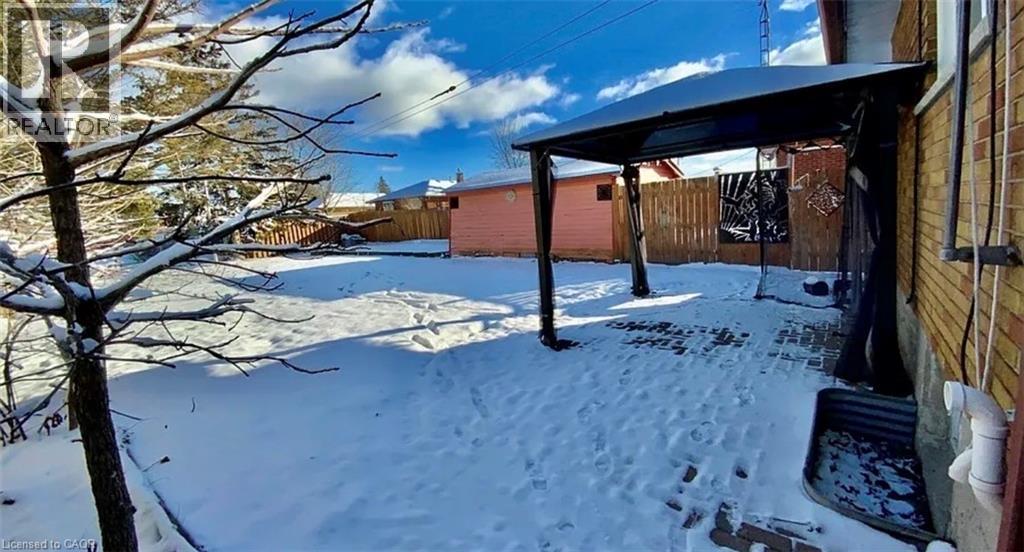 A snow-covered ground with a tree and a building in the background.
