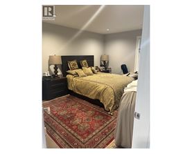 A bedroom with a large bed and a patterned rug.