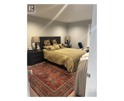 A bedroom with a large bed and a patterned rug.