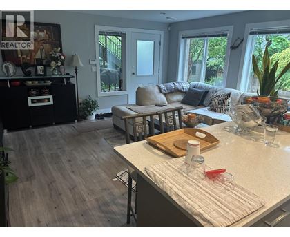 A kitchen with a table and a couch in the background.