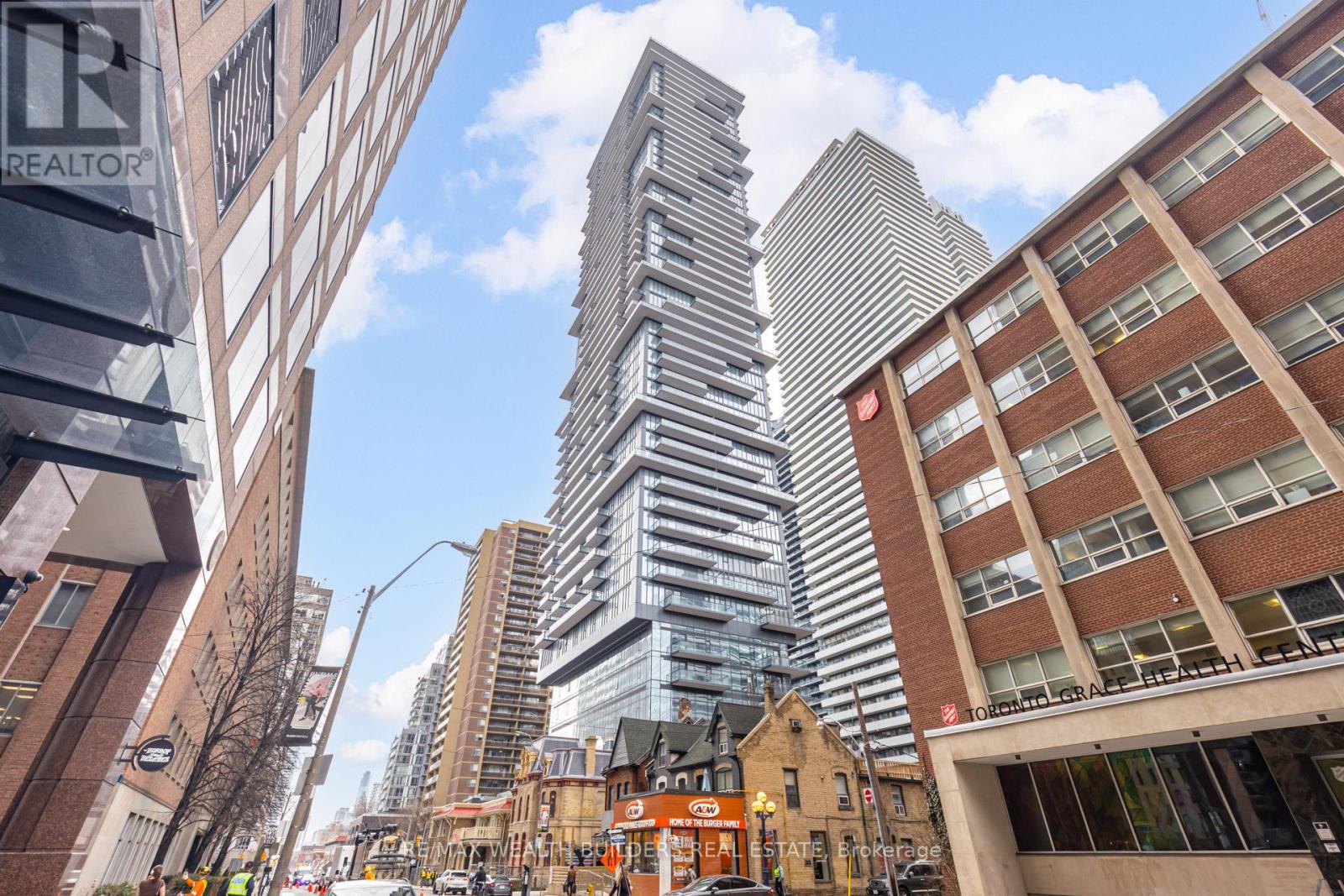A tall building with many windows stands in the middle of a city street.