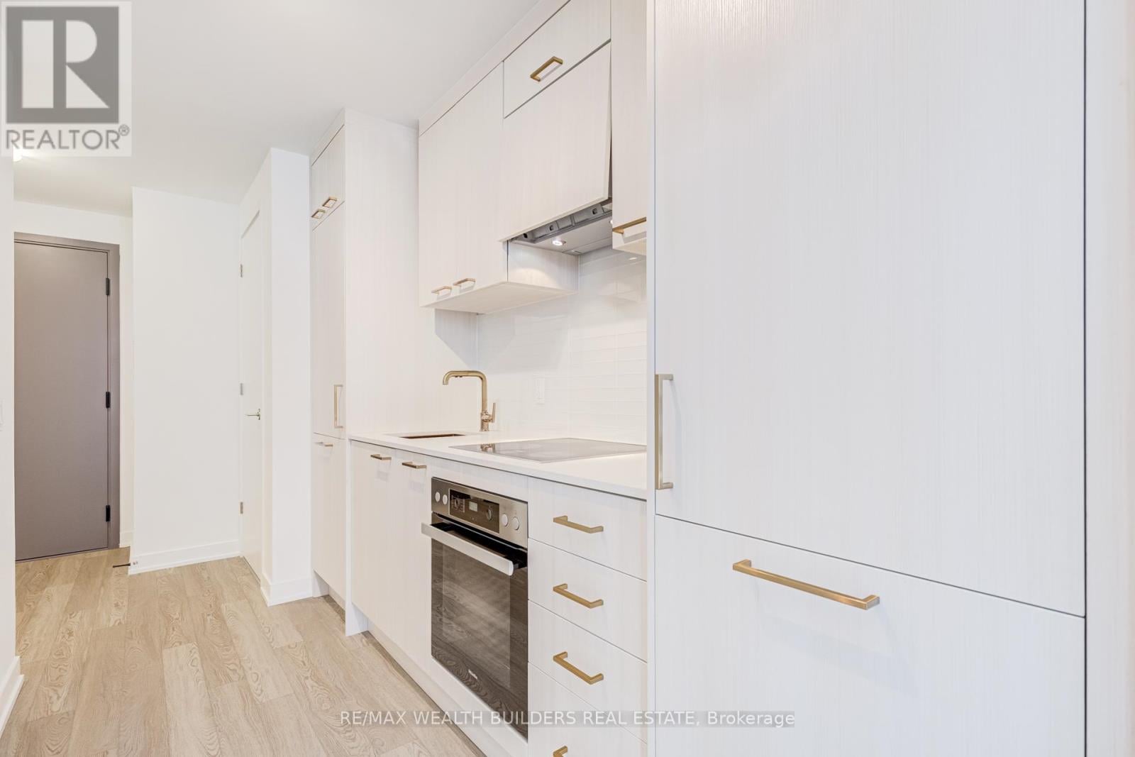 A white kitchen with a stove top oven and a refrigerator.