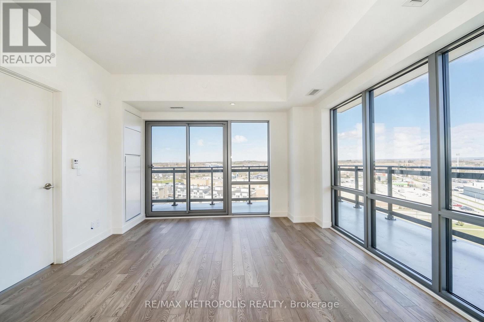 A spacious room with wooden floors and large windows overlooking a cityscape.