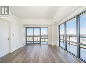 A spacious room with wooden floors and large windows overlooking a cityscape.