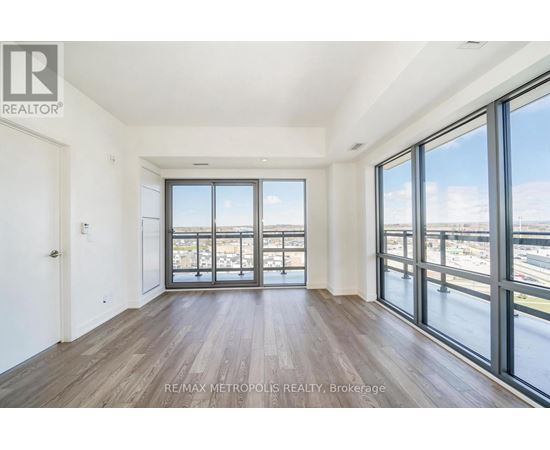 A spacious room with wooden floors and large windows overlooking a cityscape.