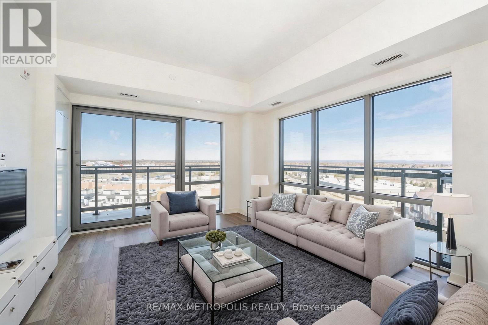 A living room with a couch, a coffee table, and a large window overlooking the city.