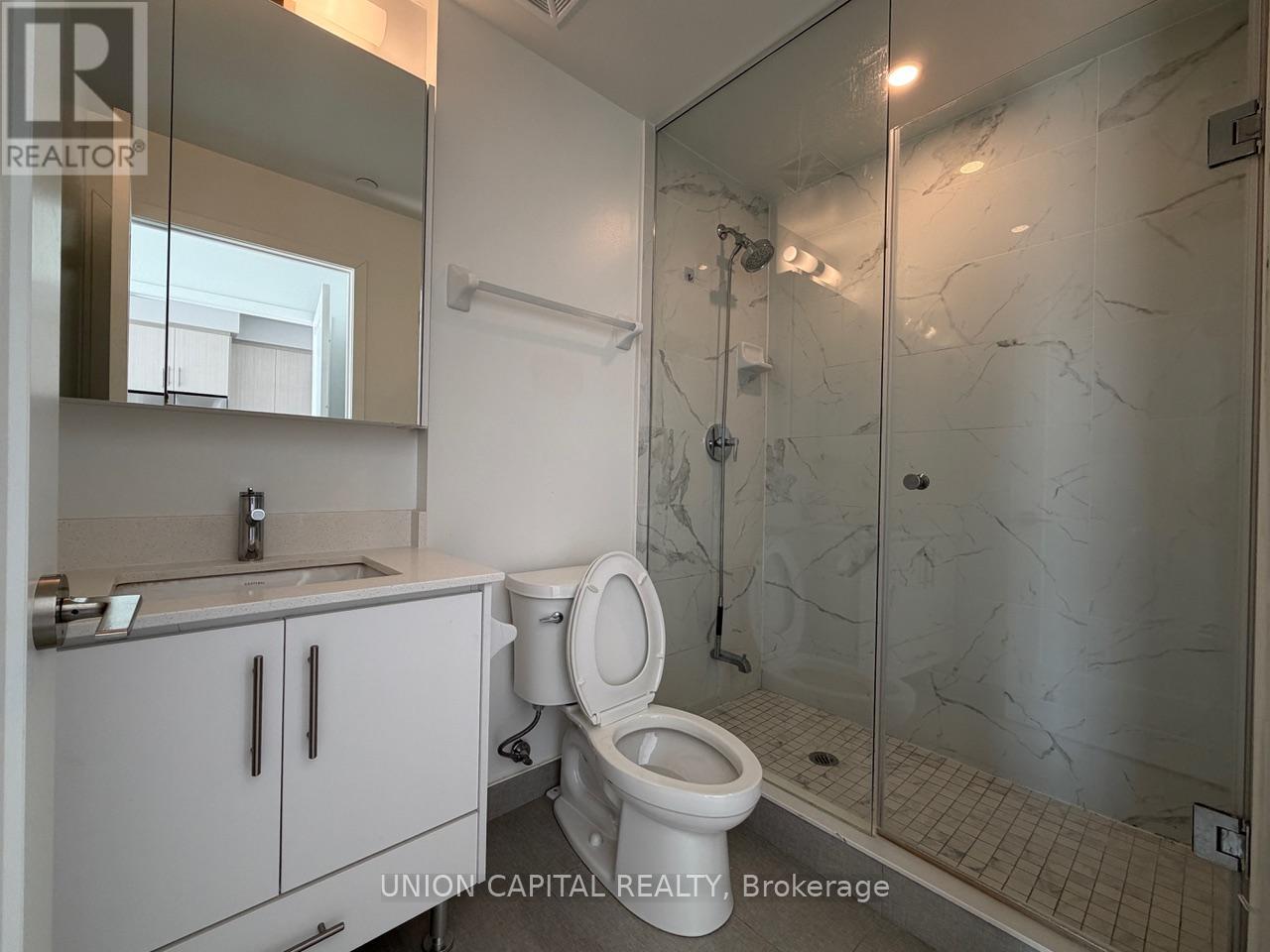 A bathroom with a toilet, sink, and shower.