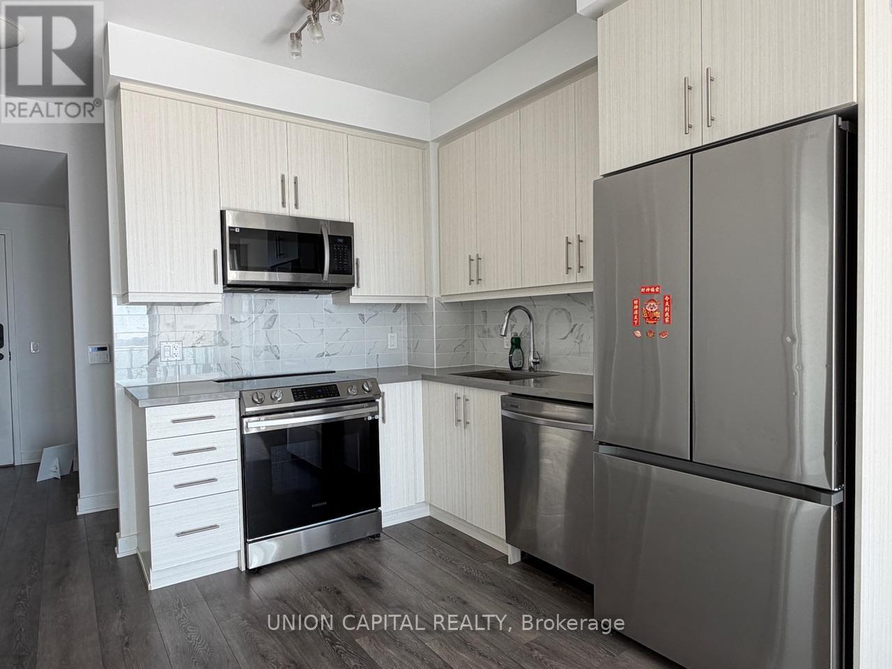 A kitchen with a refrigerator that has a red light on.