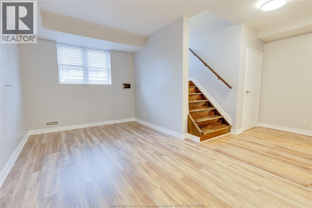 A spacious room with wooden flooring and a staircase.