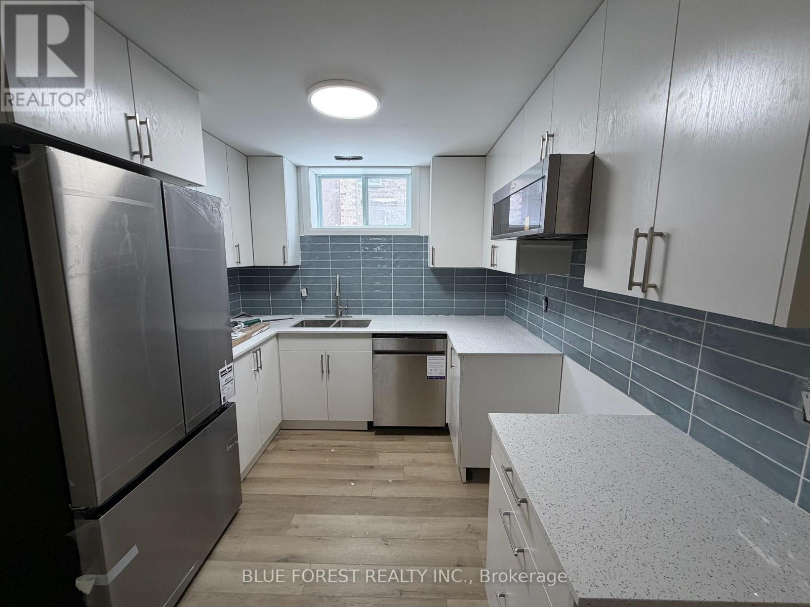 A kitchen with white cabinets and a refrigerator.