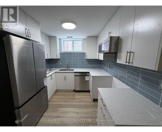 A kitchen with white cabinets and a refrigerator.