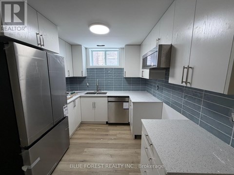 A kitchen with white cabinets and a refrigerator.