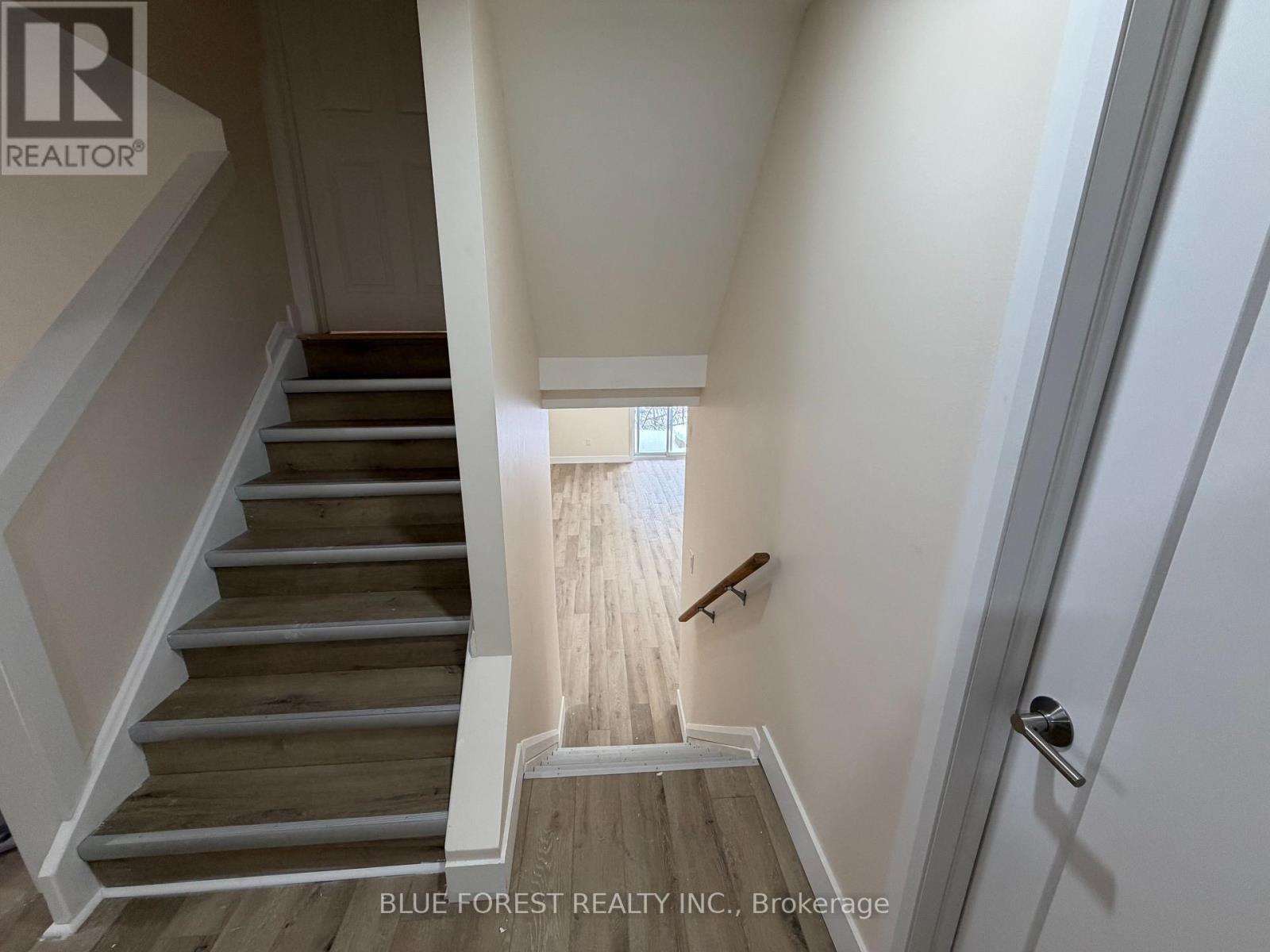 A staircase with wooden steps and white railings leads to a bright room.