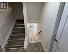 A staircase with wooden steps and white railings leads to a bright room.
