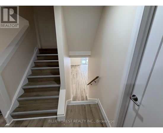 A staircase with wooden steps and white railings leads to a bright room.
