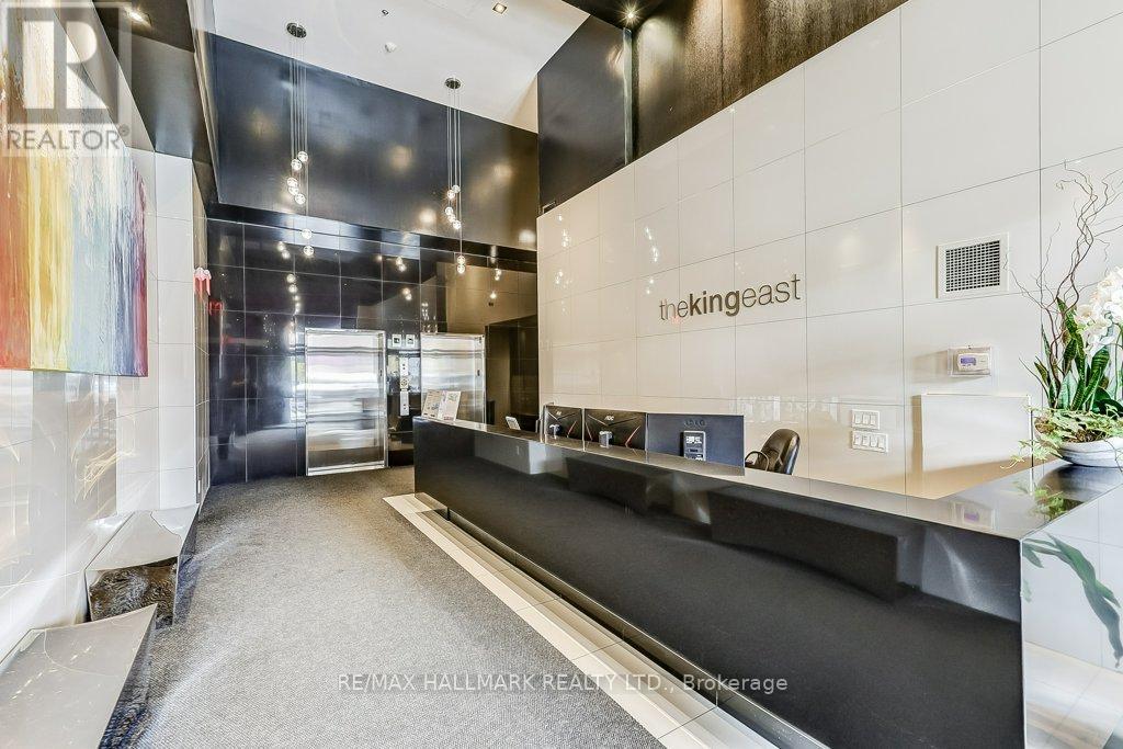 The interior of a modern office space with a reception desk and a large abstract painting on the wall.