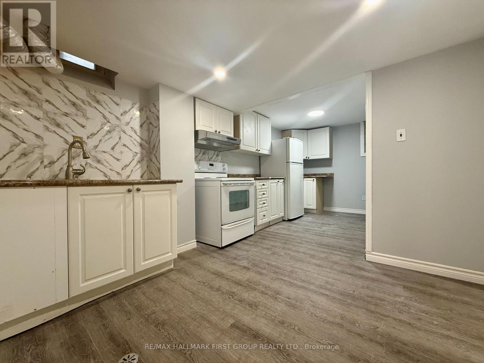 A kitchen with white cabinets and a marble backsplash.