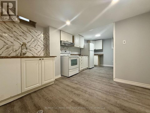 A kitchen with white cabinets and a marble backsplash.
