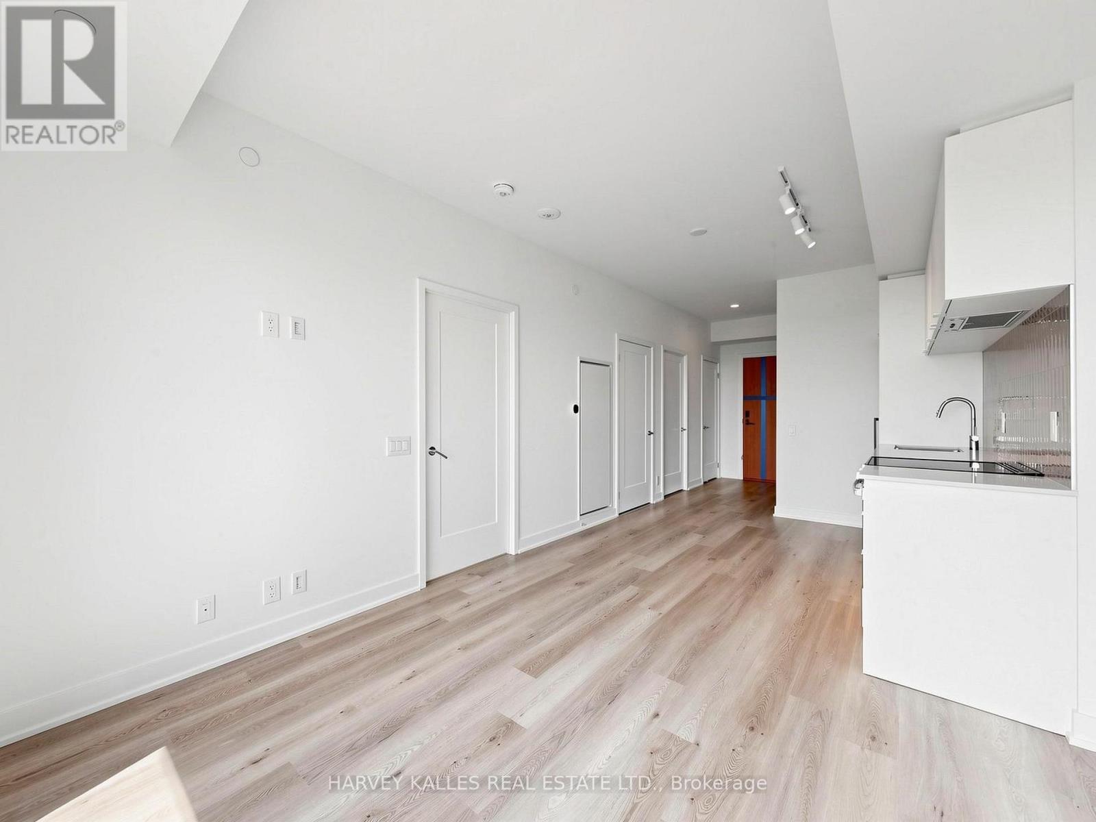 A spacious, empty room with wooden flooring and white walls.