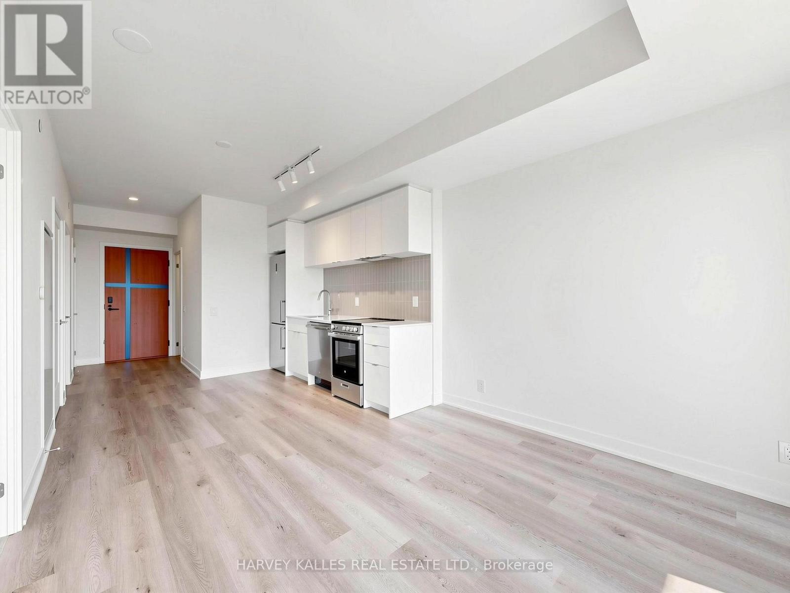 A spacious kitchen with white cabinets and a wooden floor.
