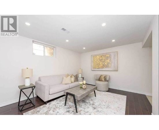 A living room with a couch, a chair, and a painting on the wall.