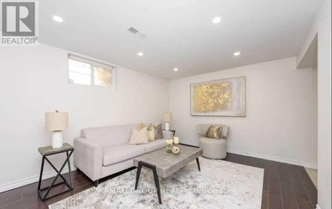 A living room with a couch, a chair, and a painting on the wall.