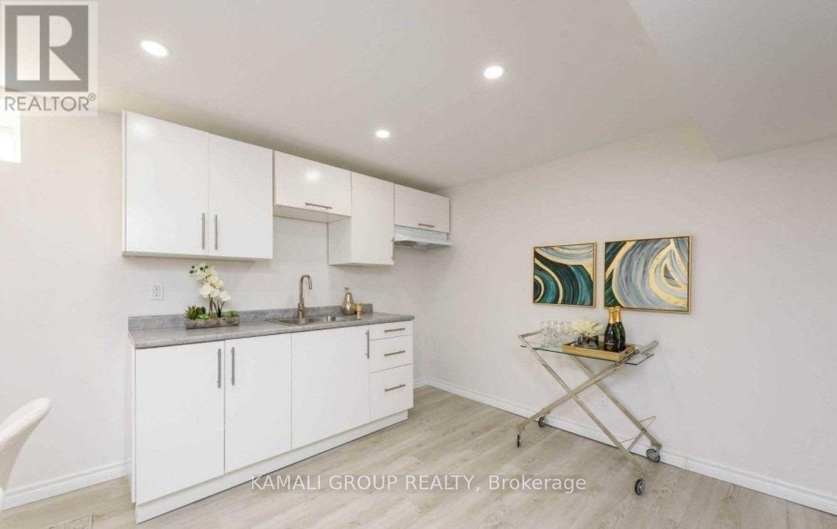 A kitchen with white cabinets and a painting on the wall.