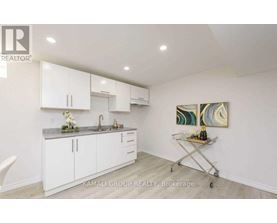 A kitchen with white cabinets and a painting on the wall.